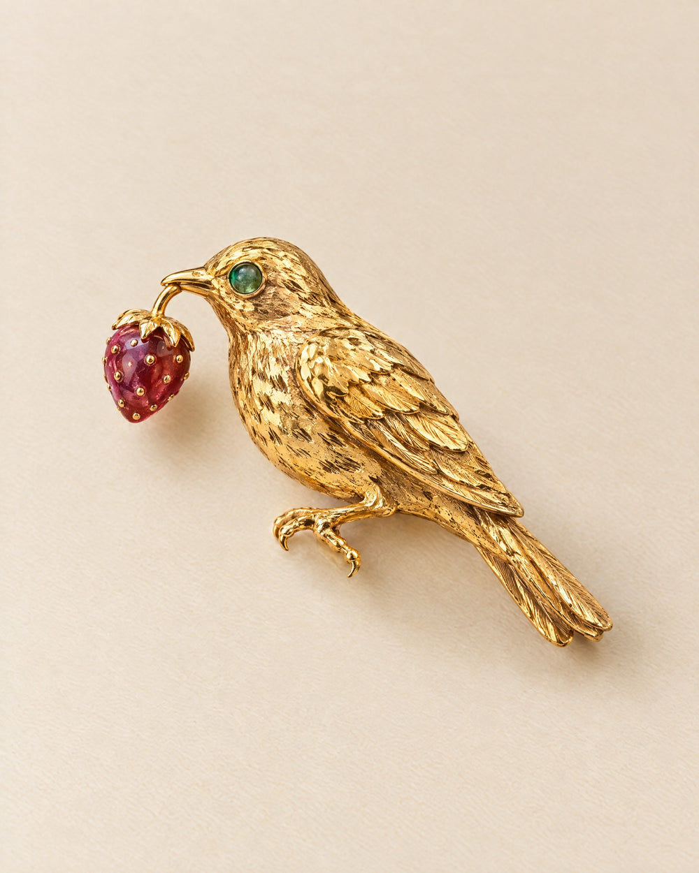 Broche La Grive: an 18ct gold thrush brooch with an emerald eye holding a ruby strawberry
