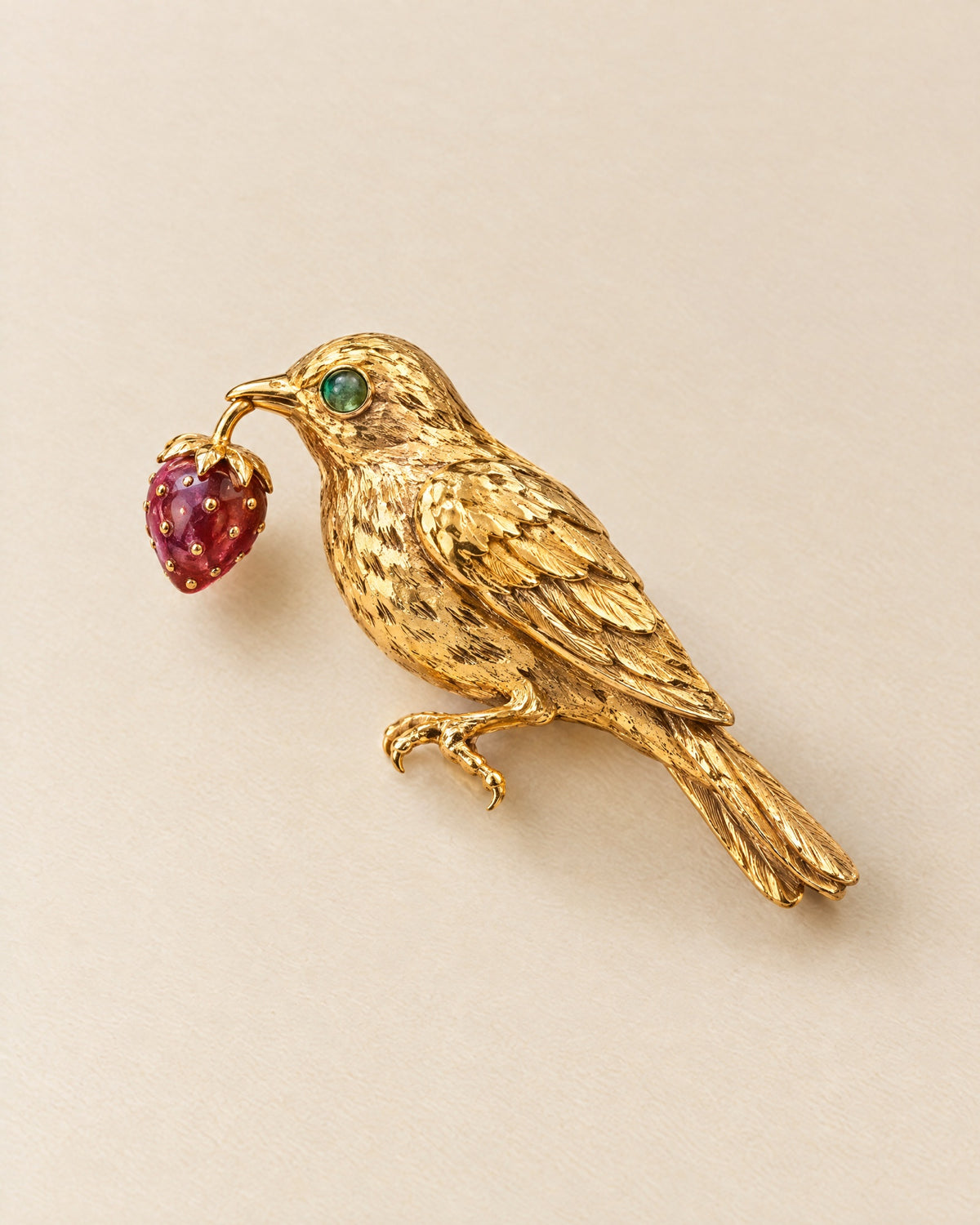 Broche La Grive: an 18ct gold thrush brooch with an emerald eye holding a ruby strawberry