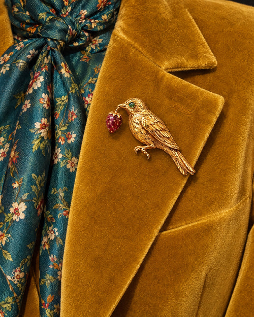 Broche La Grive pinned to a mustard velvet lapel beside a teal floral silk scarf