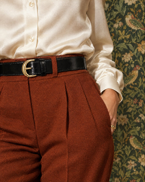 Ceinture Arche worn over a cream silk blouse tucked into rust trousers